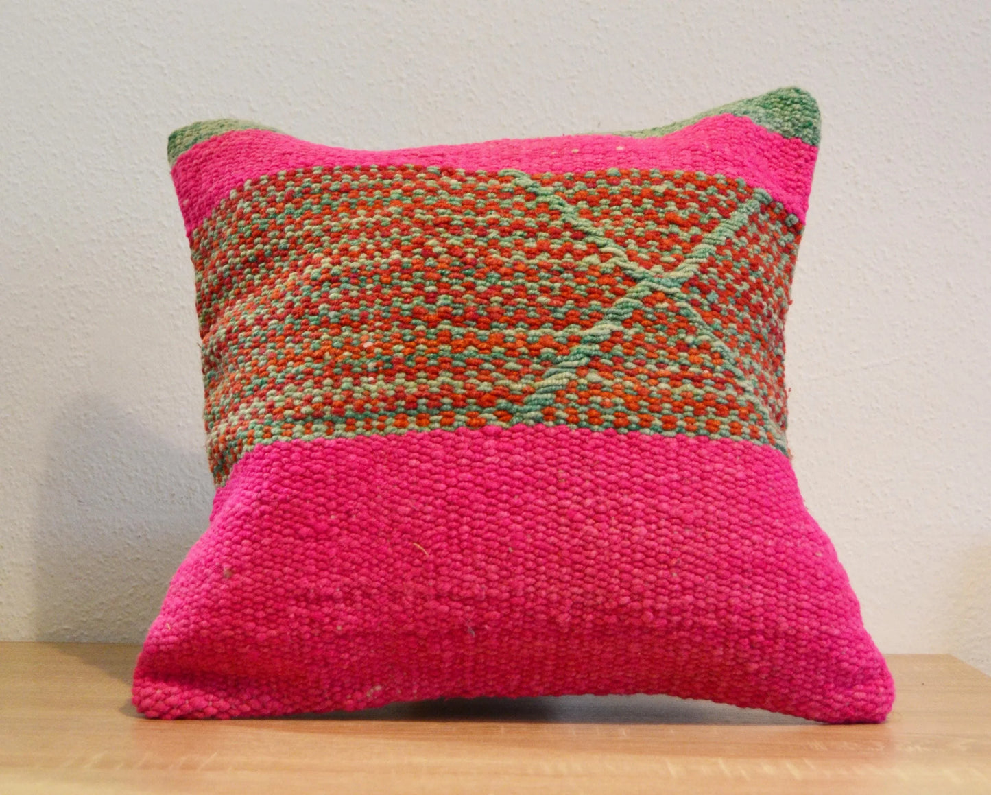 Handmade Peruvian pillow with woven alpaca fabric in bright pink and earthy tones with geometric patterns.