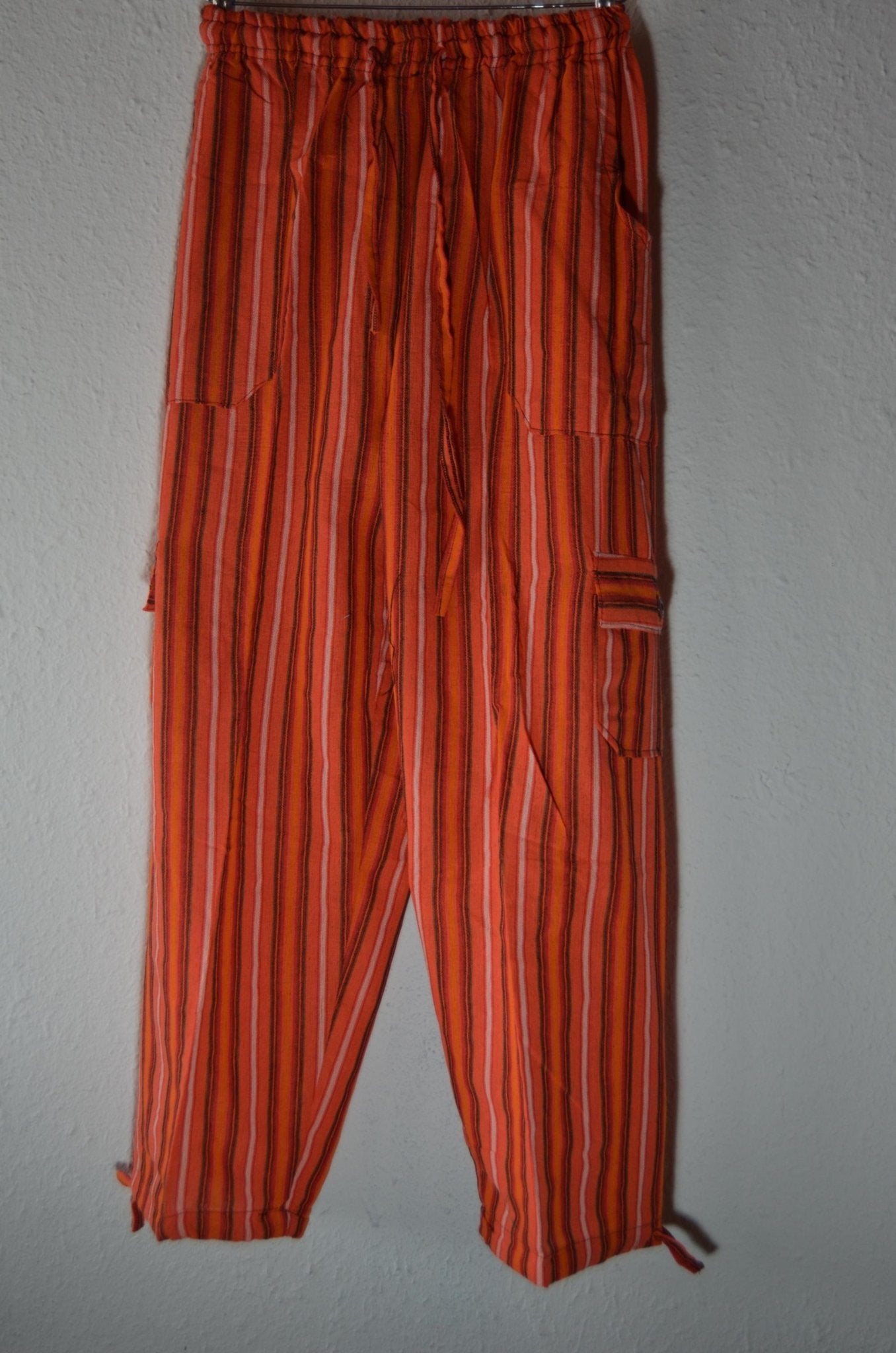 Handmade alpaca pants with orange and red vertical stripes, loose fit with side pockets and ankle ties.