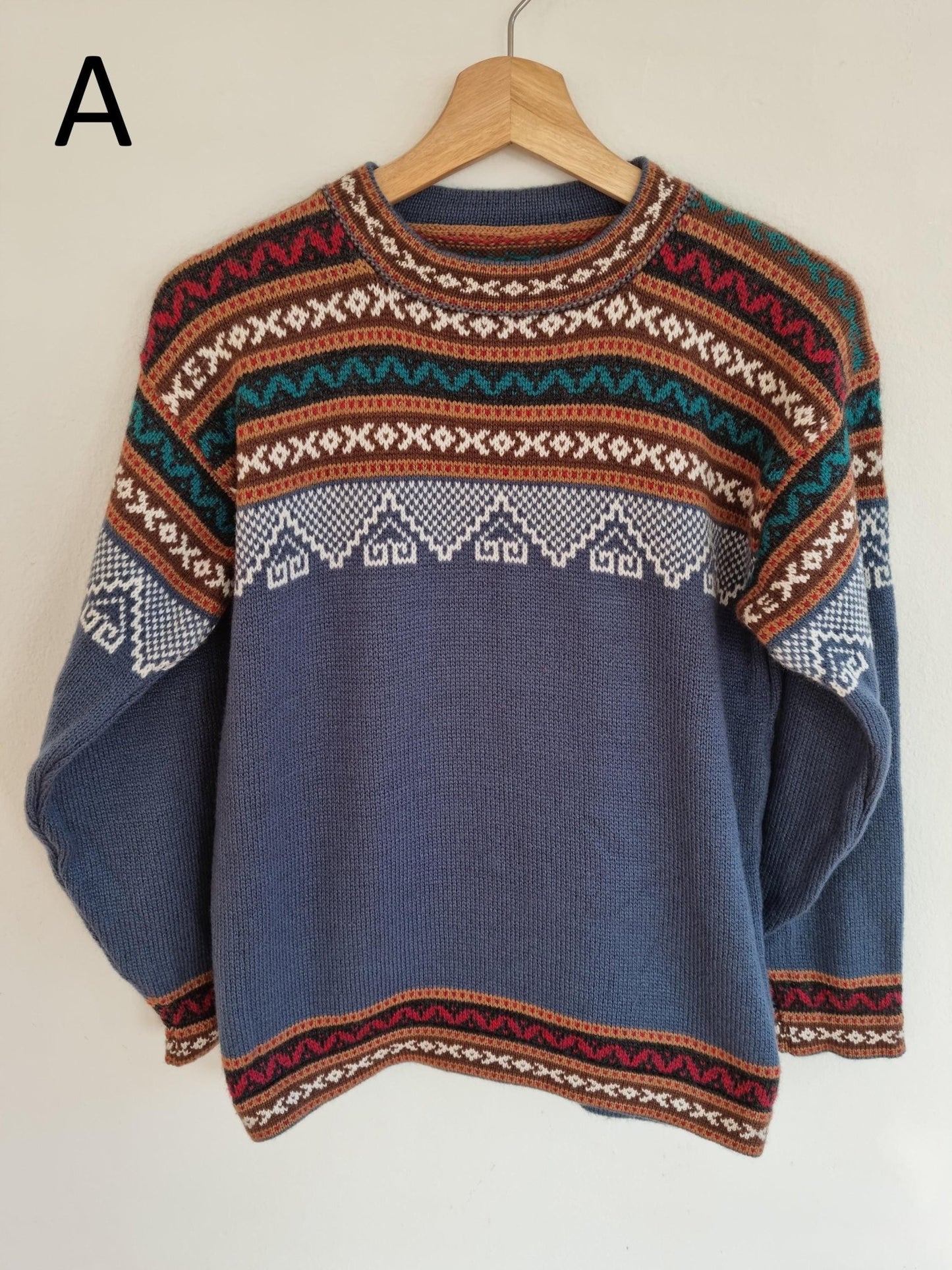 Handmade alpaca sweater with geometric patterns in rust, teal, white, and navy blue.