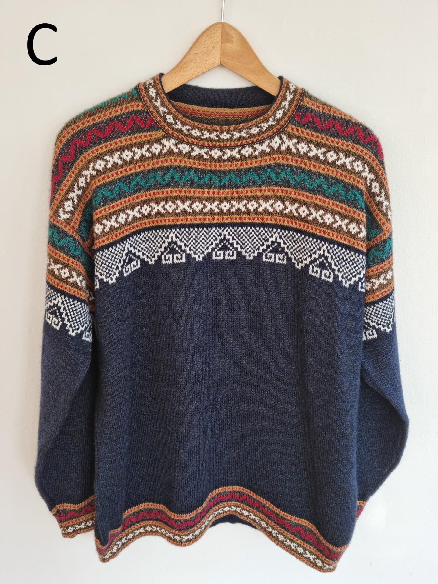 Handmade alpaca sweater with multicolor geometric patterns on navy blue background.