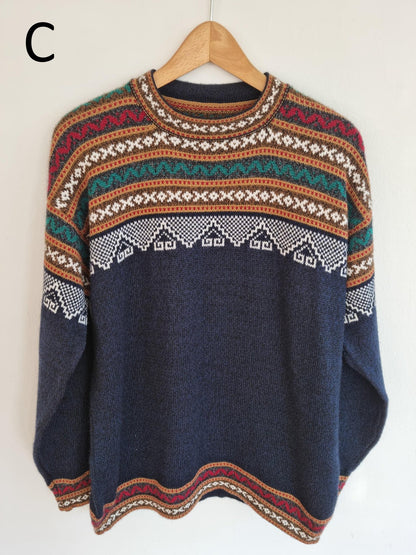 Handmade alpaca sweater with multicolor geometric patterns on navy blue background.