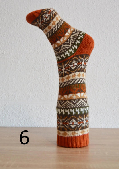 Handmade alpaca socks with brown, white, and green geometric patterns and orange accents.