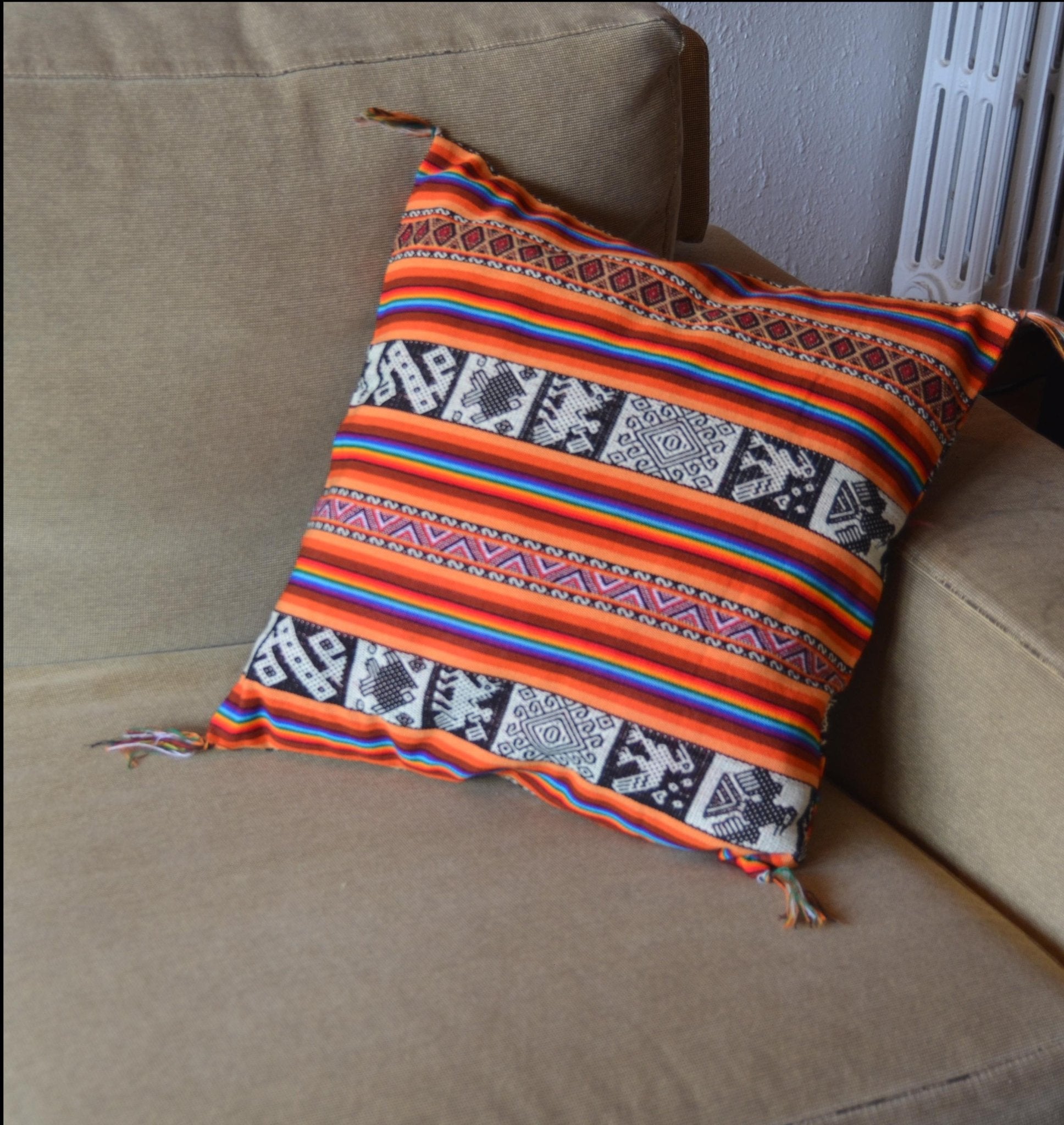 Handmade Peruvian alpaca pillow with vibrant red, orange, and black geometric stripes and tassels.