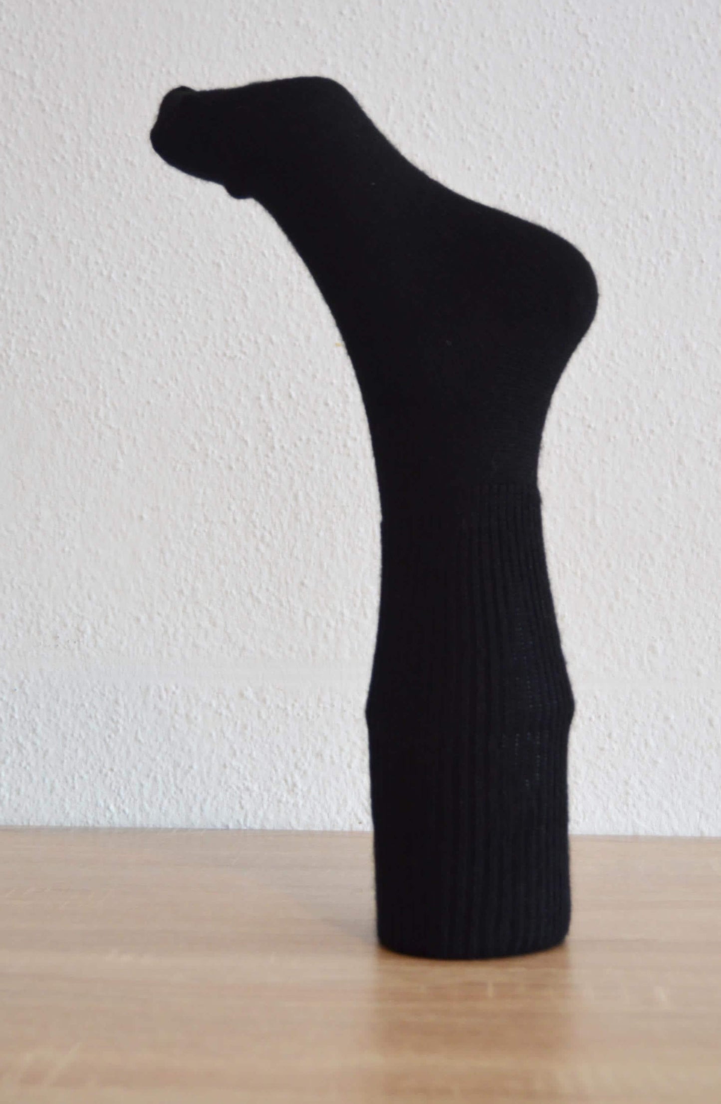 Black handmade alpaca and cotton sock with ribbed texture, mid-calf length.