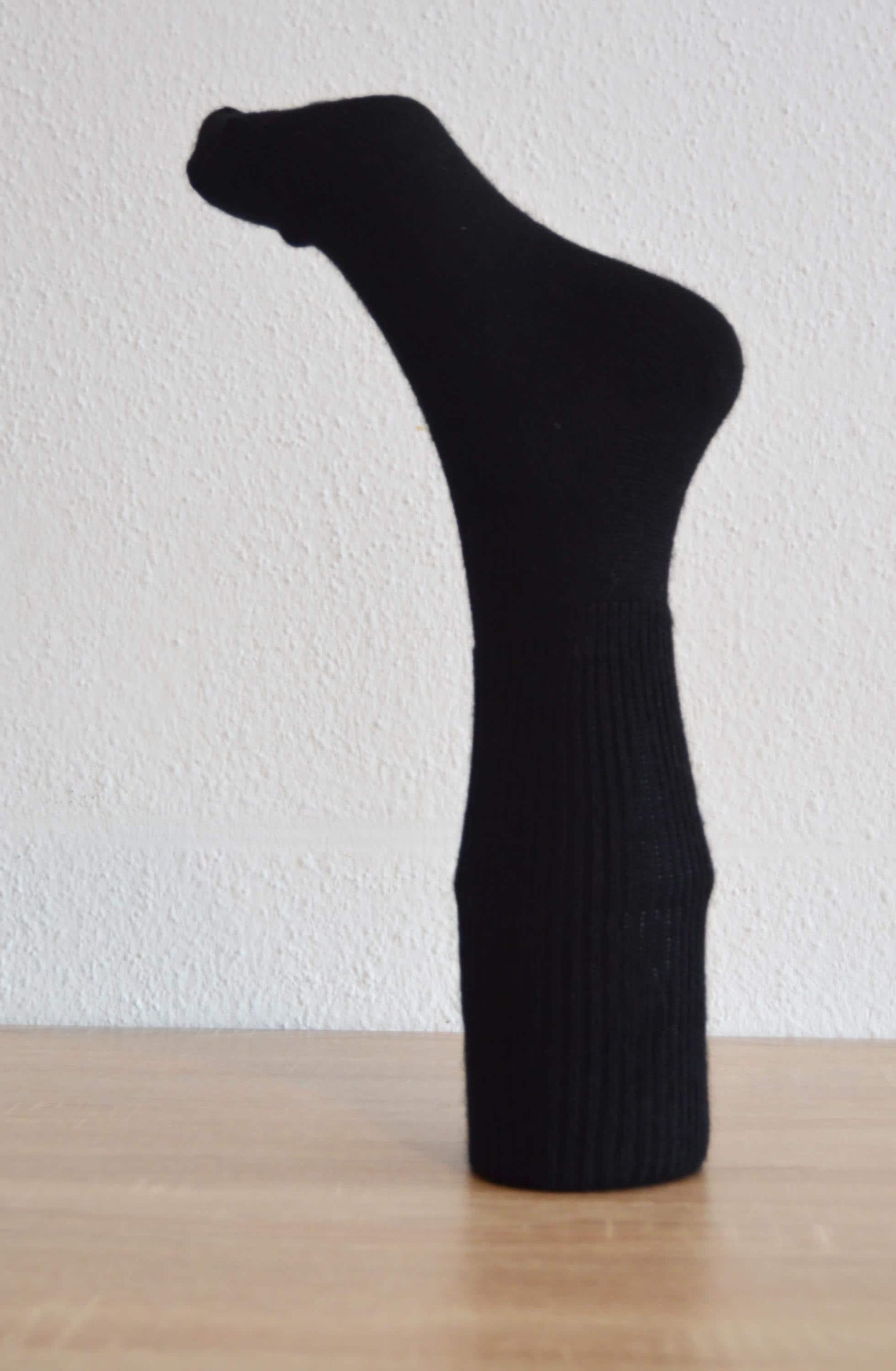 Black handmade alpaca and cotton sock with ribbed texture, mid-calf length.