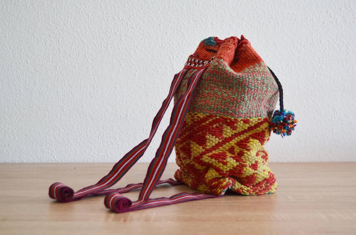 Handmade alpaca shoulder bag with colorful geometric Andean patterns and braided straps.