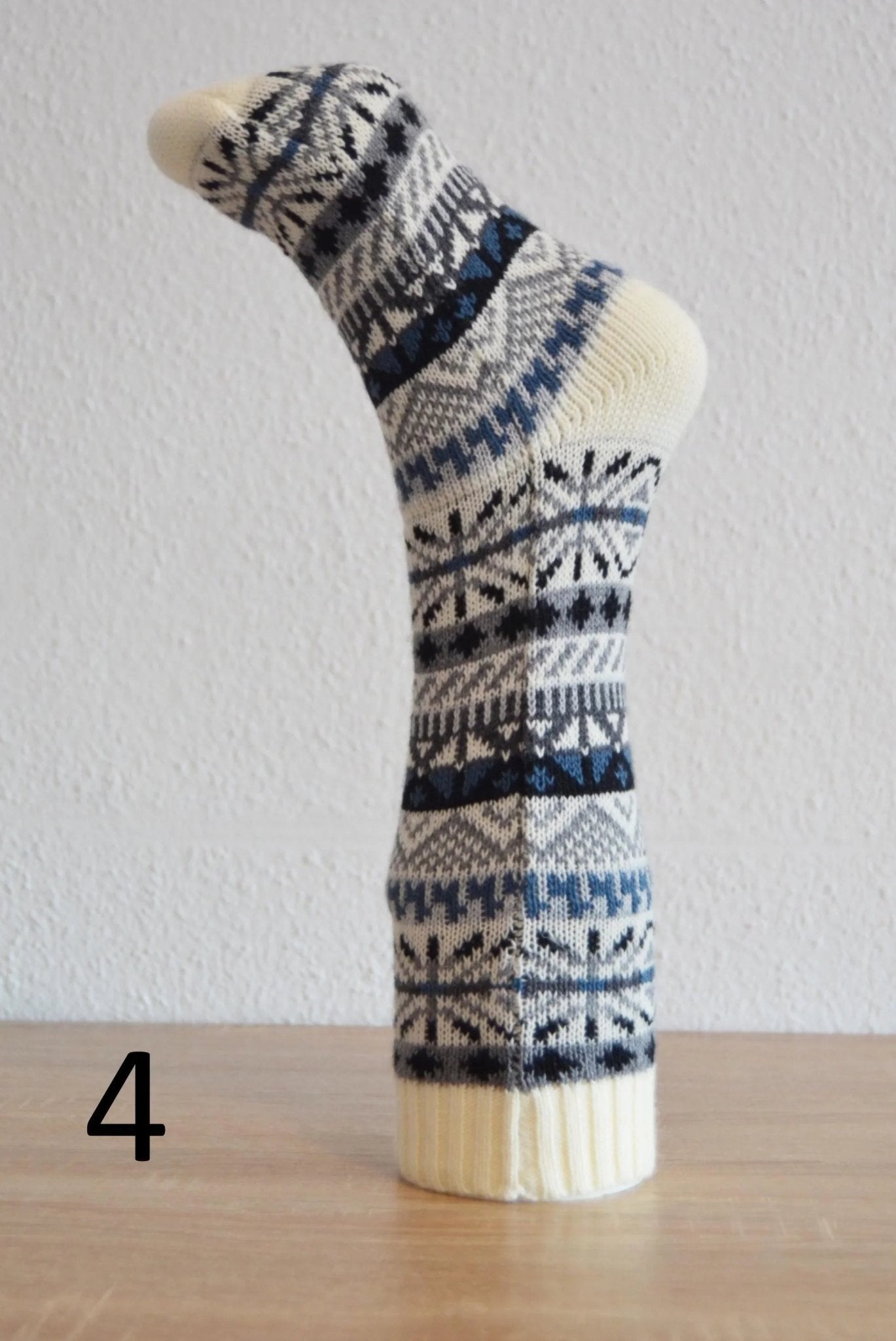 Handmade alpaca sock with blue and black geometric patterns on cream background.