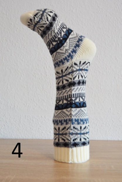 Handmade alpaca sock with blue and black geometric patterns on cream background.