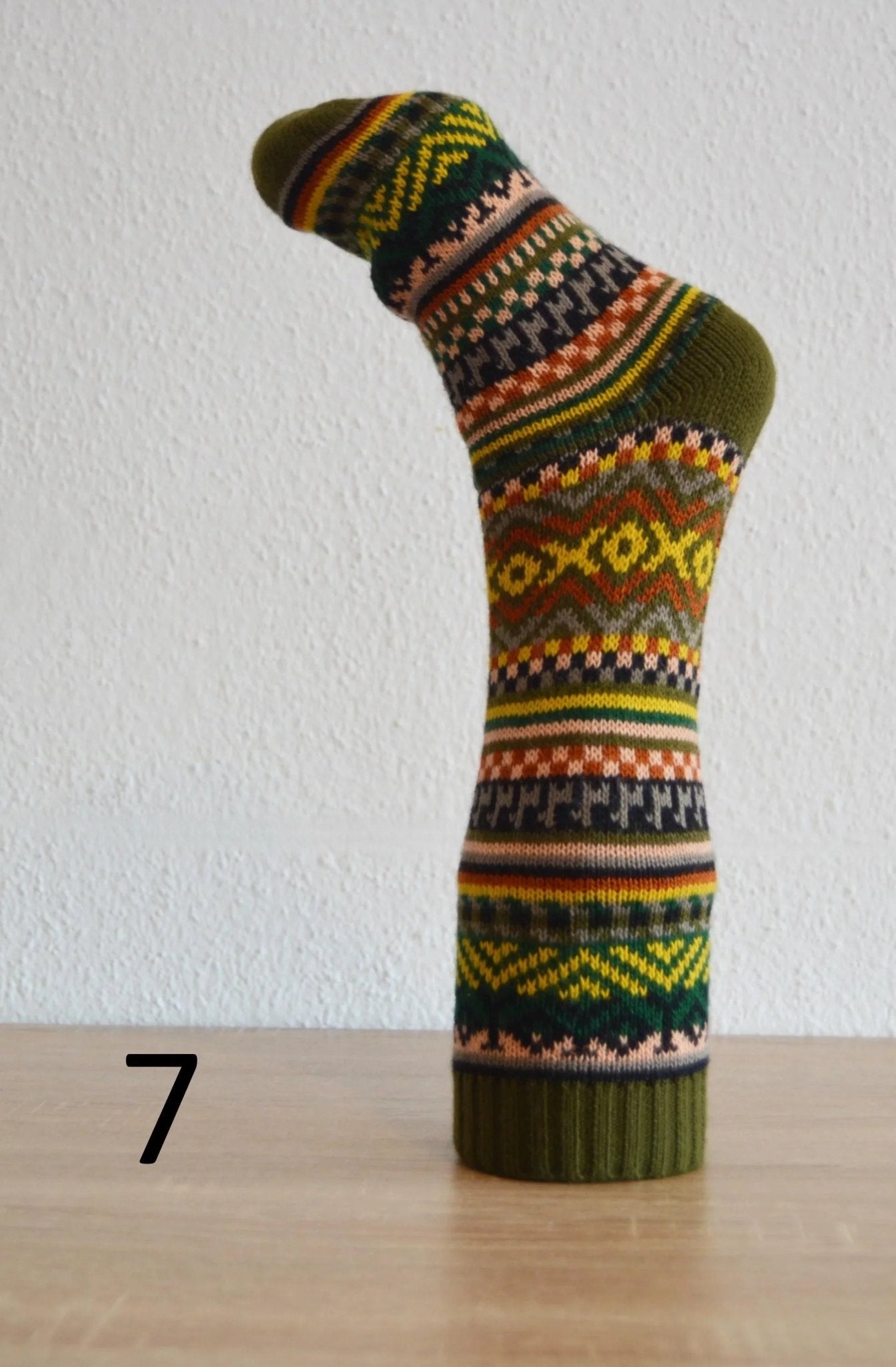 Handmade alpaca sock with green, yellow, and orange geometric patterns and ribbed cuff.