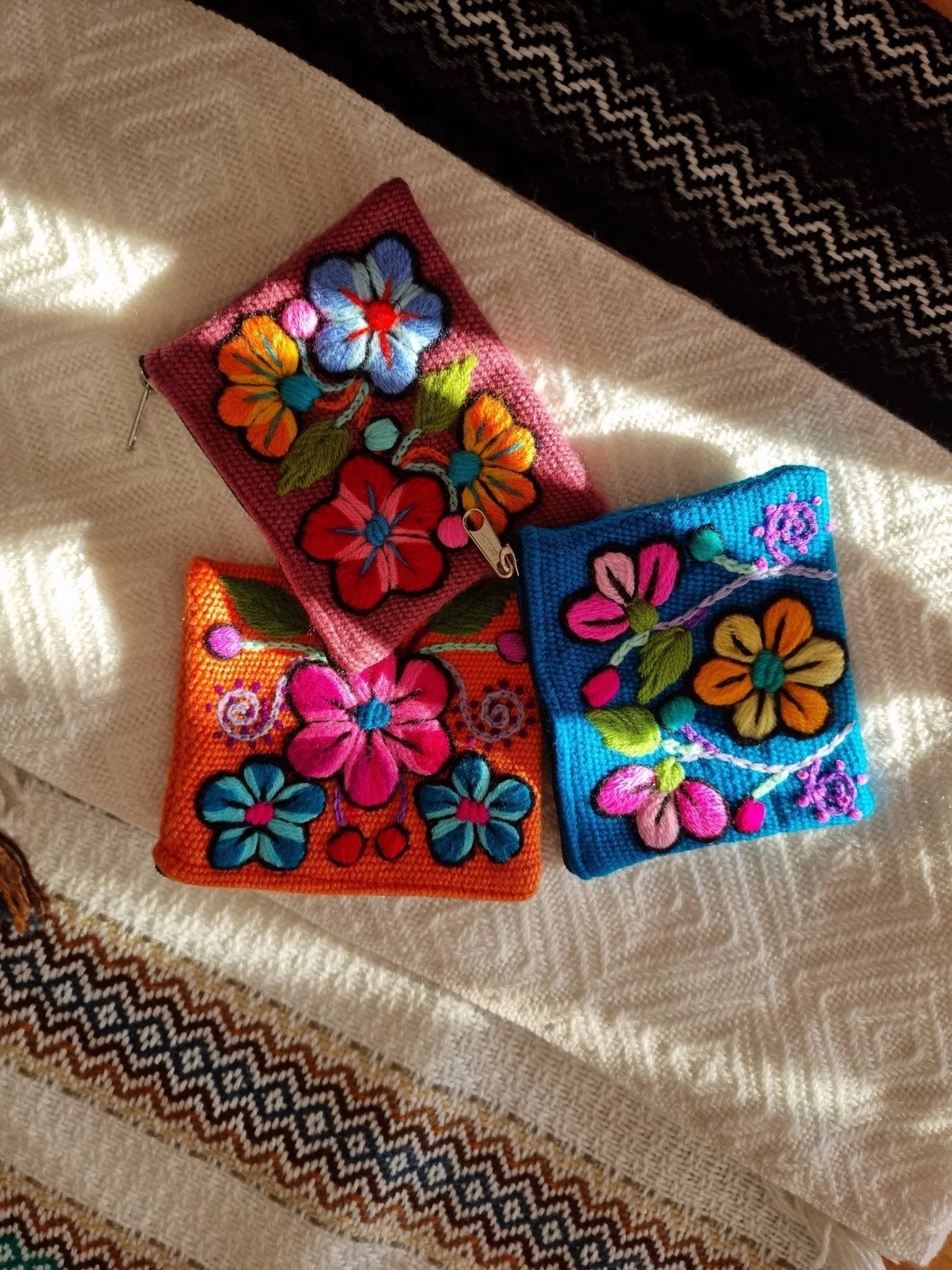 Handmade alpaca wool wallet with vibrant floral embroidery in orange, red, and blue colors.