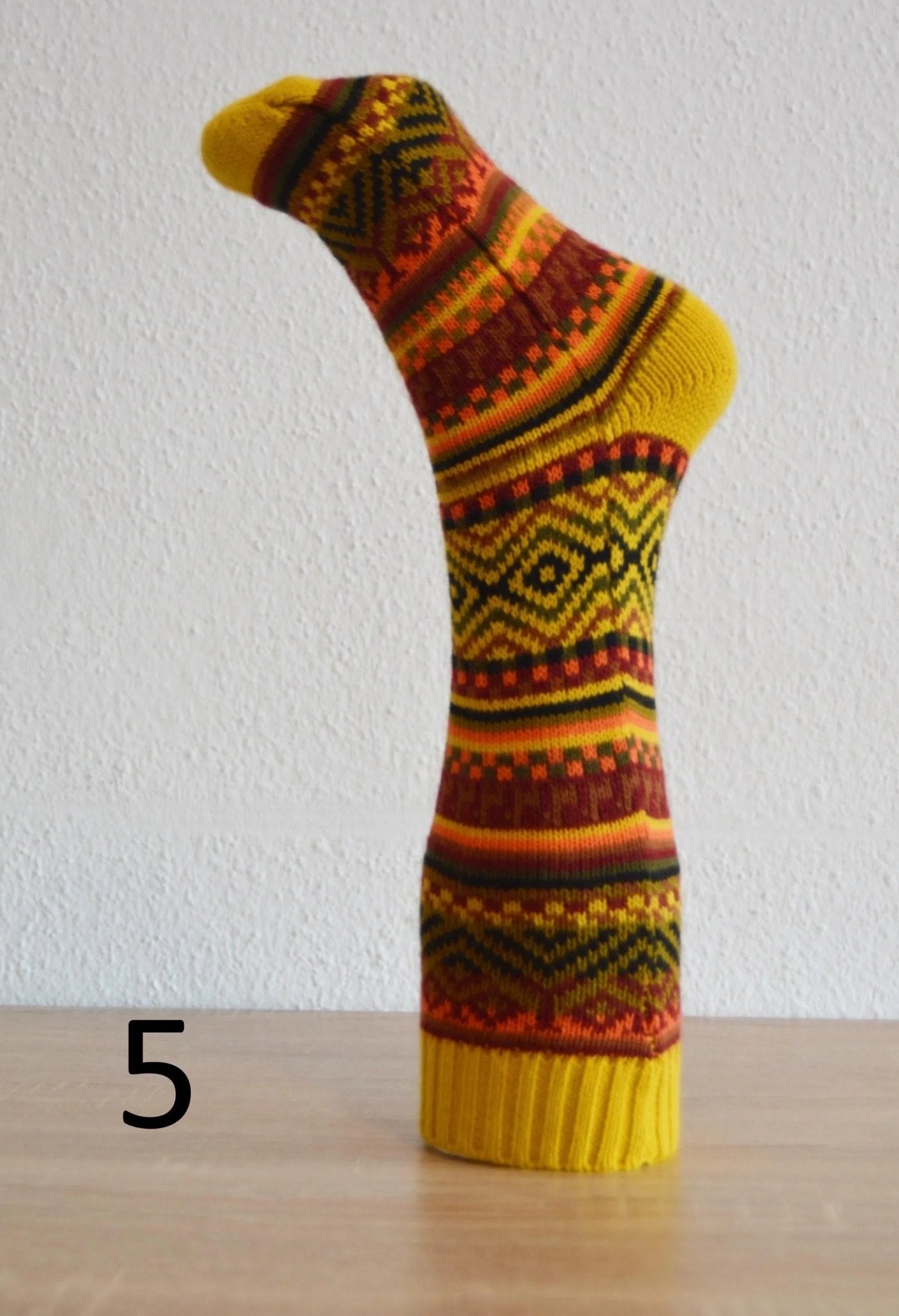 Handmade alpaca sock in warm yellow, orange, and brown with intricate geometric patterns.
