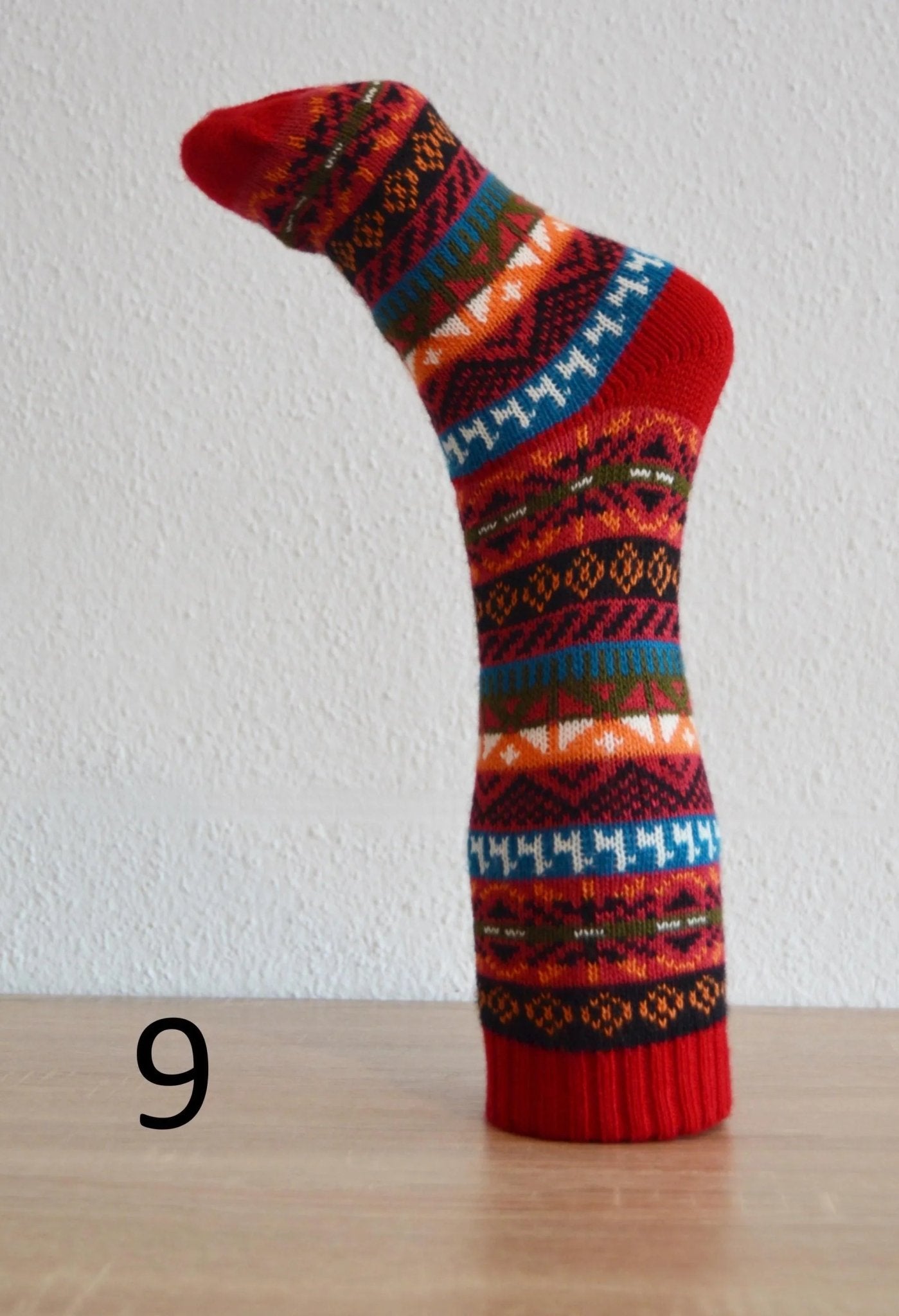 Handmade alpaca sock with red, orange, blue, and black geometric patterns.