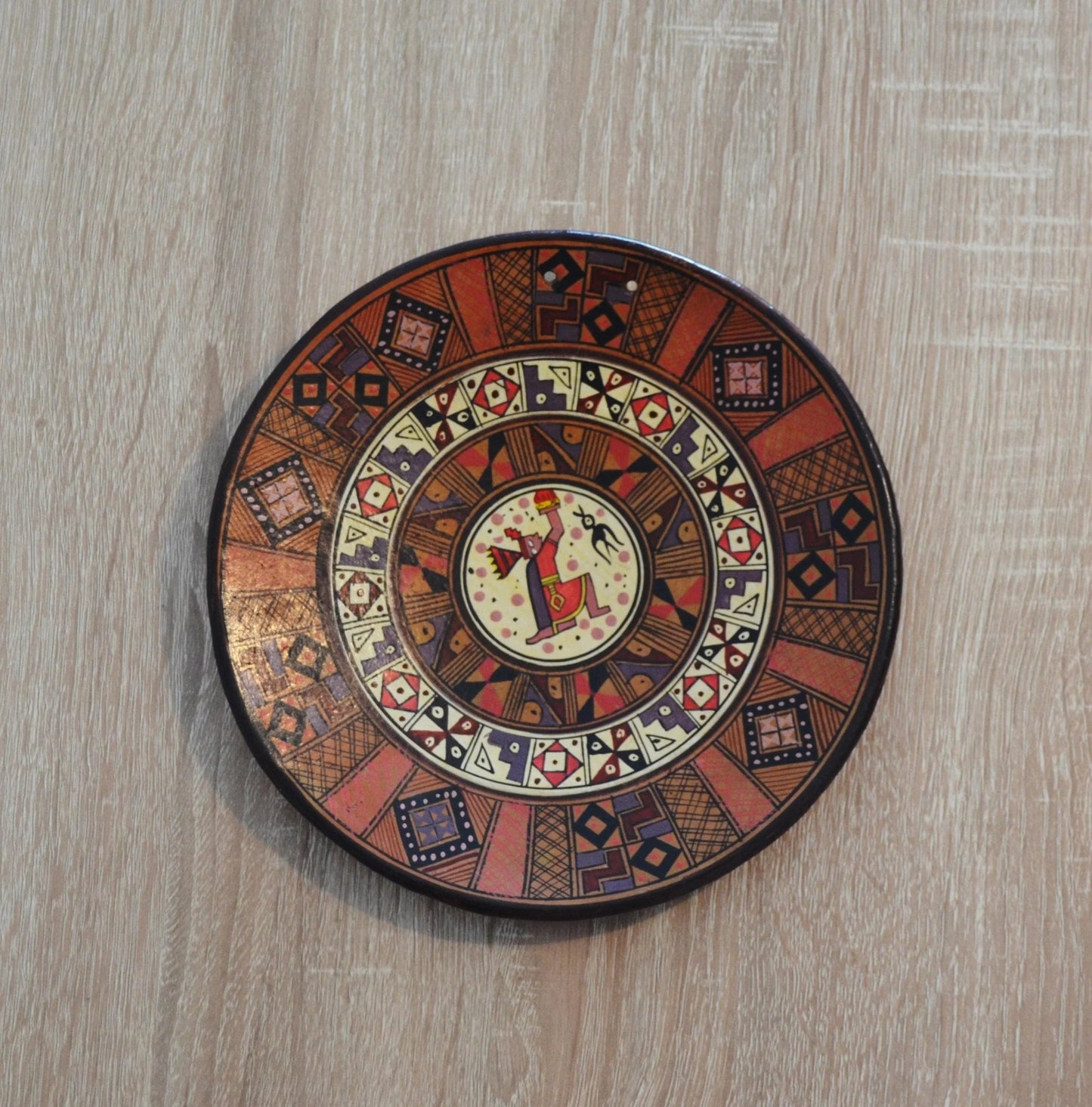 Handmade Peruvian terracotta ceramic plate with colorful alpaca and geometric patterns.