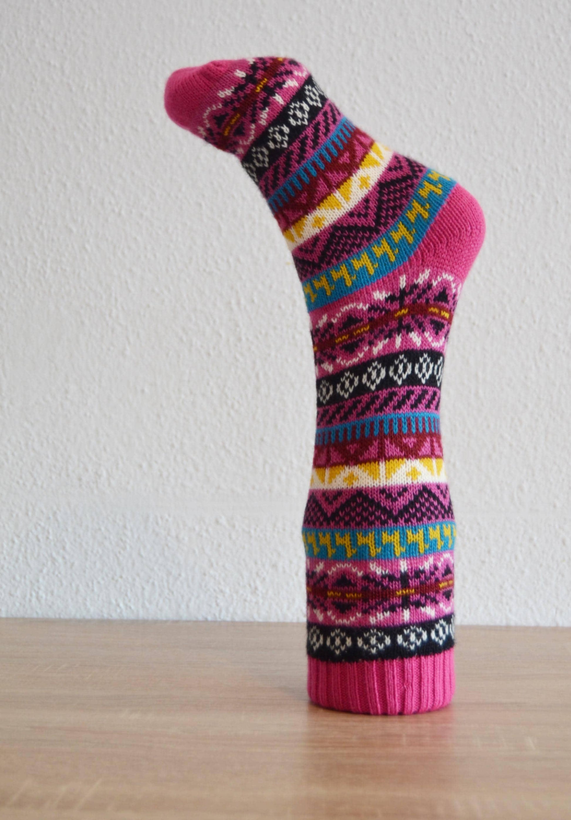 Colorful handmade alpaca sock with geometric and zigzag patterns in pink, blue, yellow, and black.
