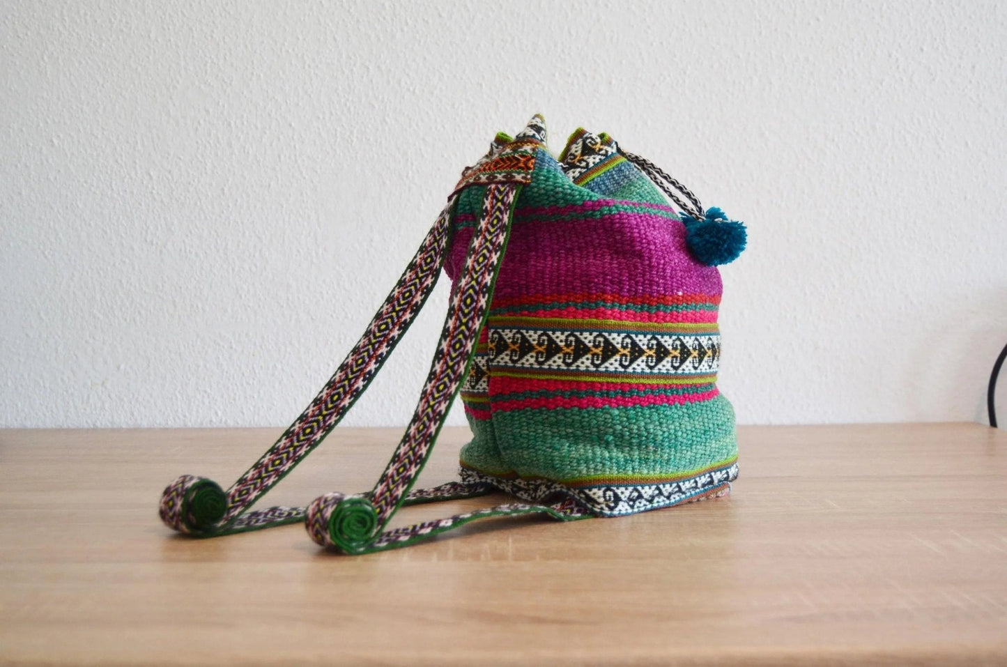 Handmade colorful alpaca shoulder bag with traditional Peruvian patterns and pom-pom details.