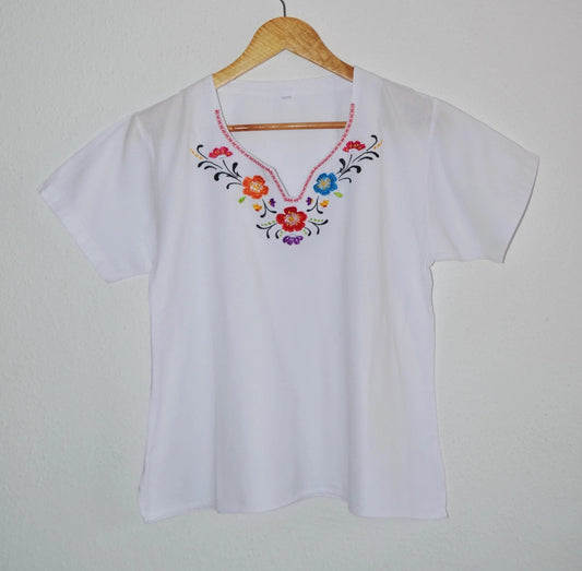 White handmade cotton blouse with colorful floral alpaca embroidery and V-neckline.