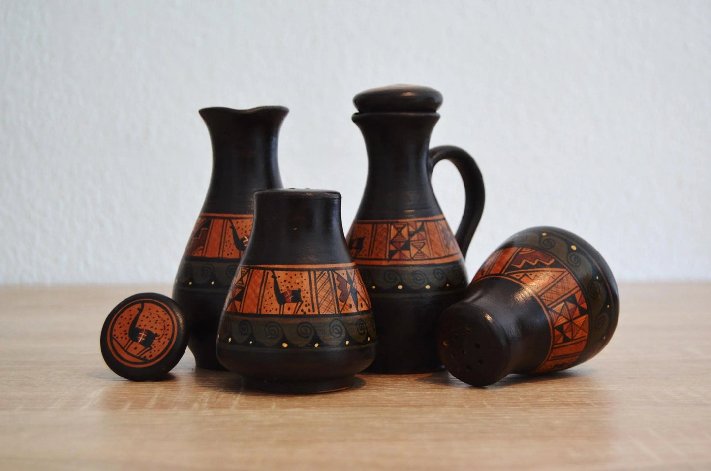 Set of handmade Peruvian terracotta pottery with black and orange alpaca motifs.