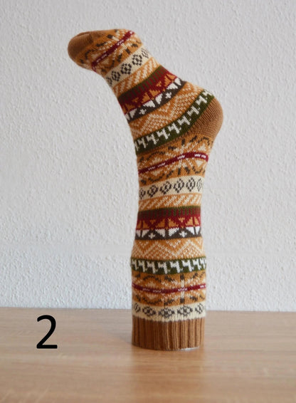 Handmade alpaca sock with multicolor geometric patterns in warm earth tones.