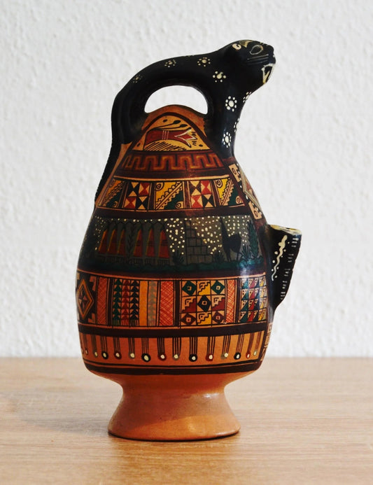 Handmade terracotta ceramic jug shaped like an alpaca with colorful geometric patterns and earthy tones.