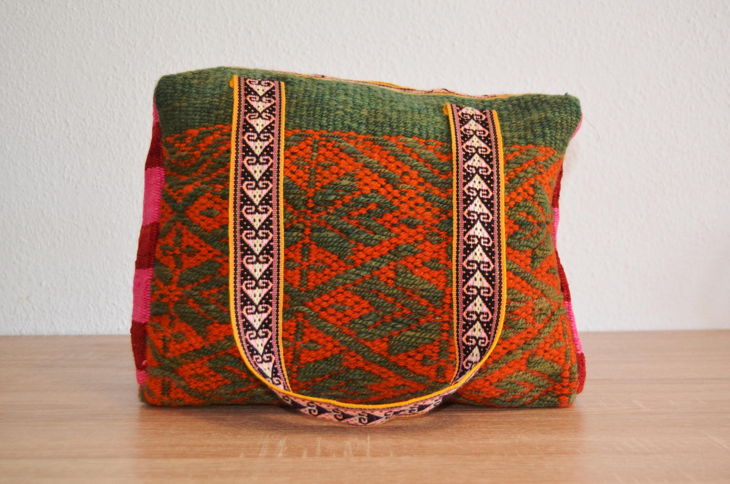 Handmade alpaca wool shoulder bag with red and green geometric patterns and ethnic woven straps.