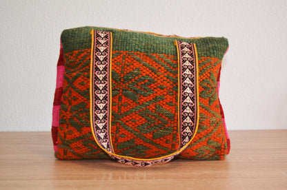 Handmade alpaca wool shoulder bag with red and green geometric patterns and ethnic woven straps.