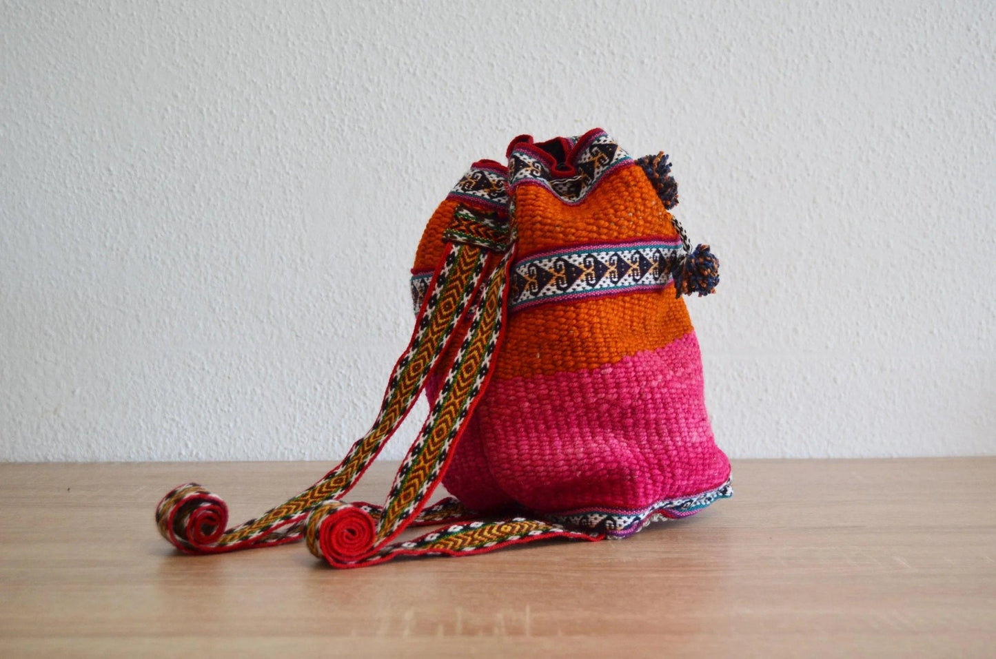 Handmade small alpaca shoulder bag with vibrant pink and orange Andean textile design.