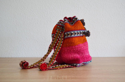 Handmade small alpaca shoulder bag with vibrant pink and orange Andean textile design.