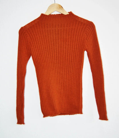 Handmade burnt orange alpaca turtleneck sweater with ribbed knit texture.