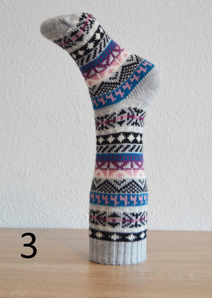 Handmade alpaca sock with multicolor geometric patterns in blue, pink, black, and white.