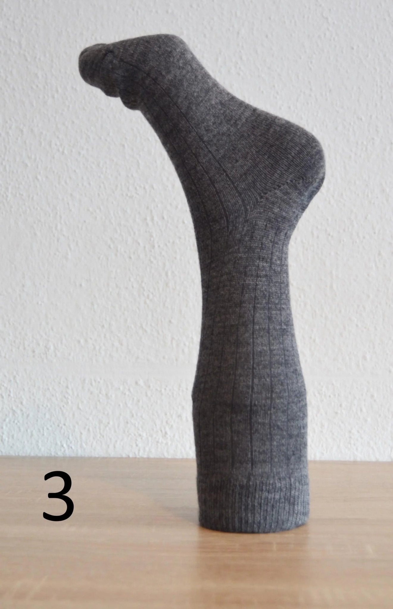 Handmade dark gray alpaca and cotton sock with ribbed texture, mid-calf length.