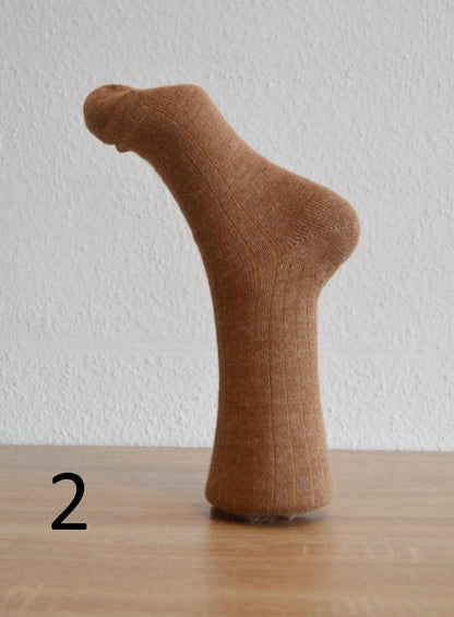 Brown handmade alpaca and cotton sock displayed on foot mannequin against white background.