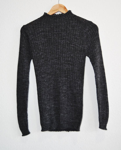 Black handmade alpaca turtleneck sweater with ribbed texture and long sleeves.