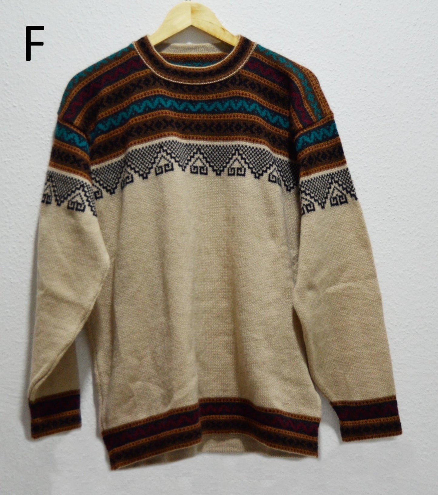 Handmade alpaca sweater with beige base and multicolor geometric patterns on yoke and cuffs.